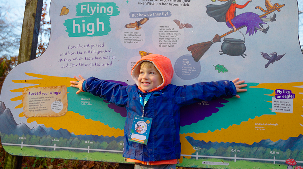 Child comparing his wing span against a sign